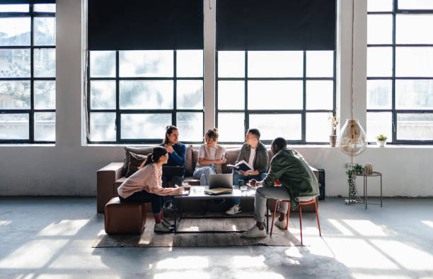 A diverse group of young adults engaged in a collaborative work session in a bright, modern co-working space.